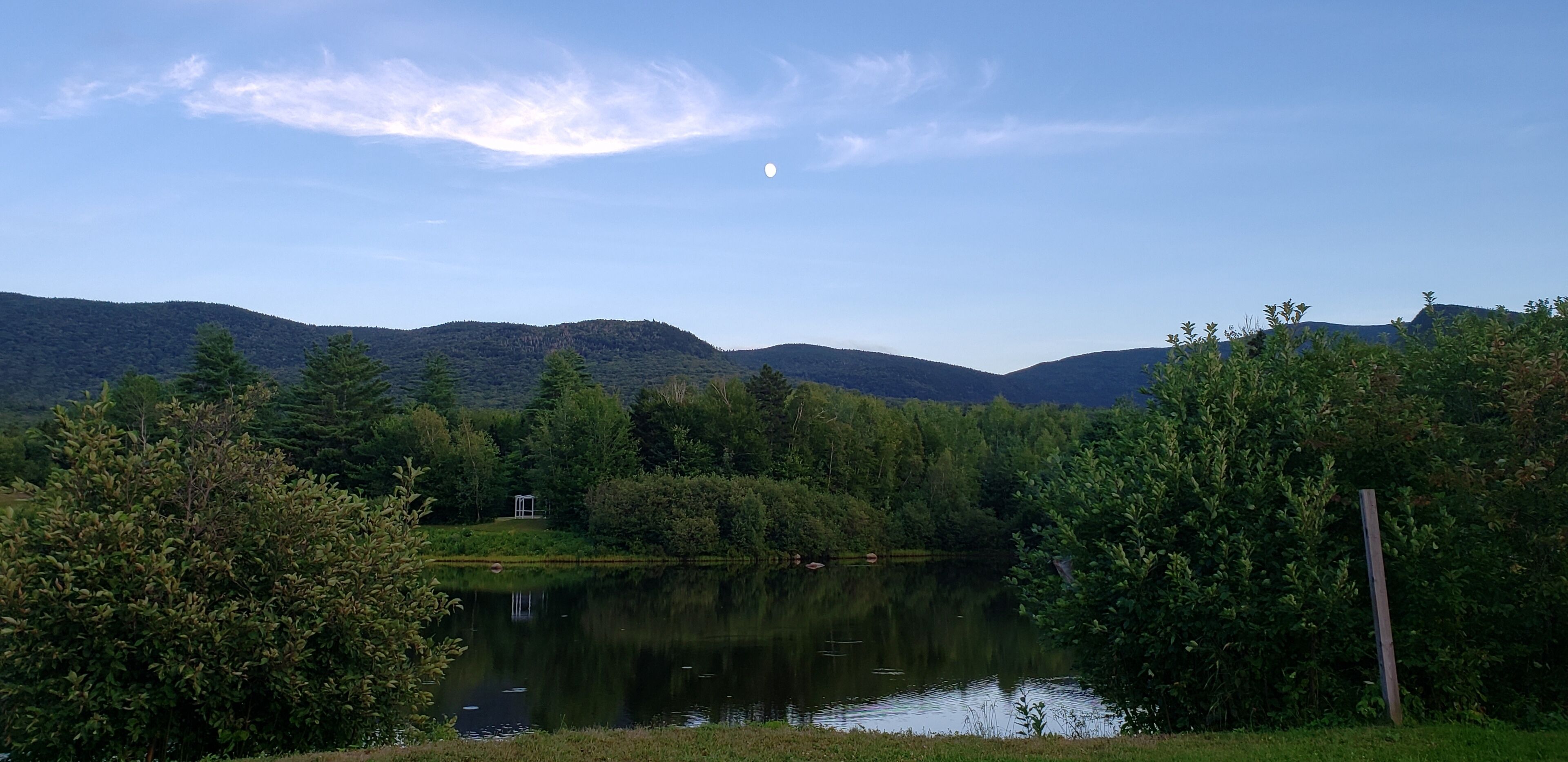 A serene lake surrounded by lush greenery and hills.