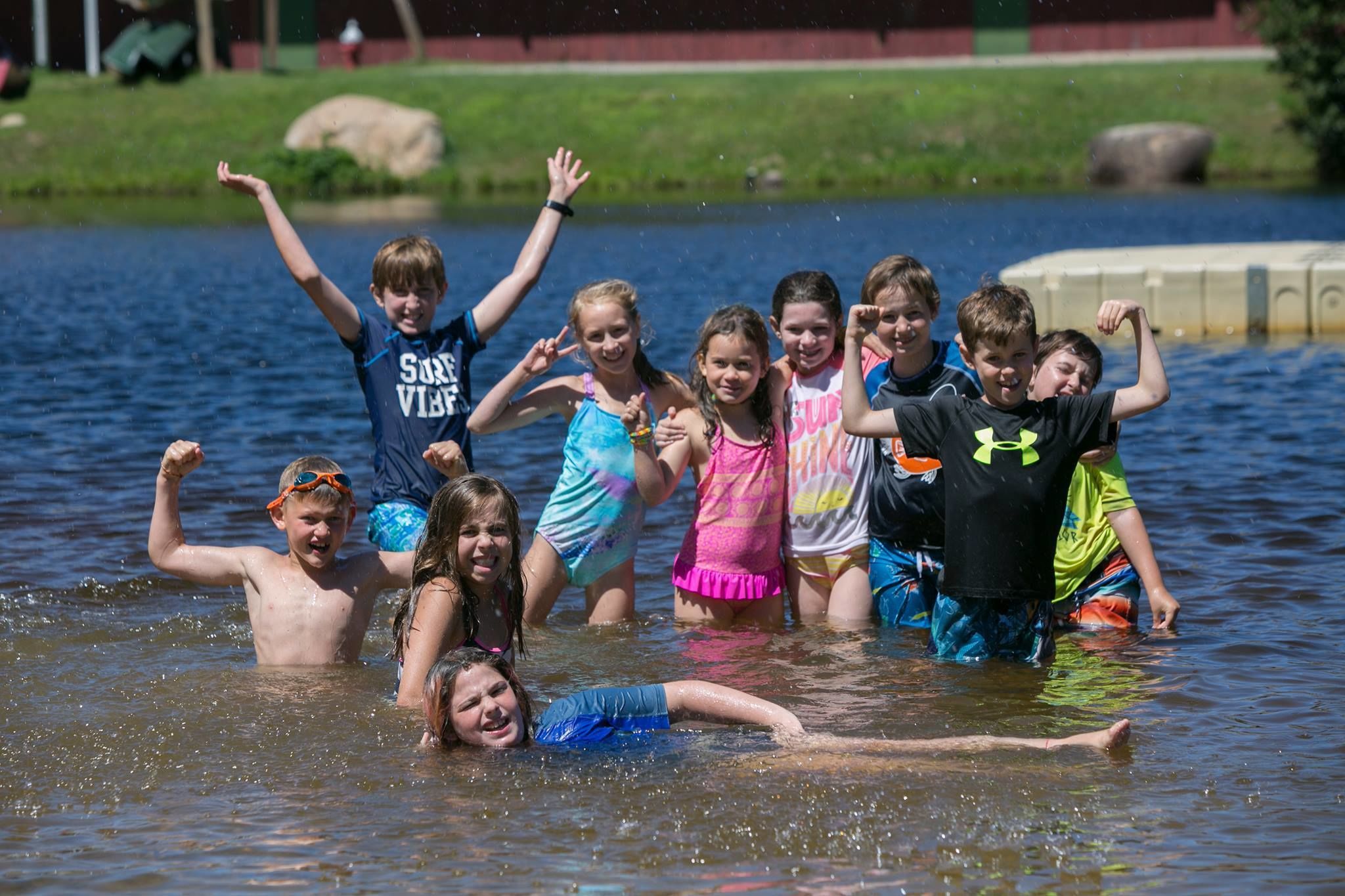 A group of children playing in a body of water surrounded by greenery.