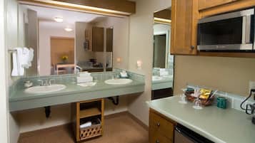 Une salle de bain d’hôtel avec deux lavabos, un four à micro-ondes et une coiffeuse avec des tiroirs.