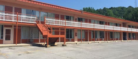 A motel with a red exterior, multiple balconies, and a parking lot.