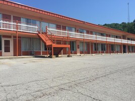 A motel with a red exterior, multiple balconies, and a parking lot.