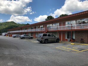 A motel with a parking lot, a red building, and a white fence.