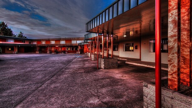 A modern building with a covered outdoor area and a parking lot. - Curly Redwood Lodge (Crescent City)