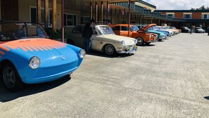 A row of vintage cars parked in a lot with a modern building in the background. - Curly Redwood Lodge (Crescent City)