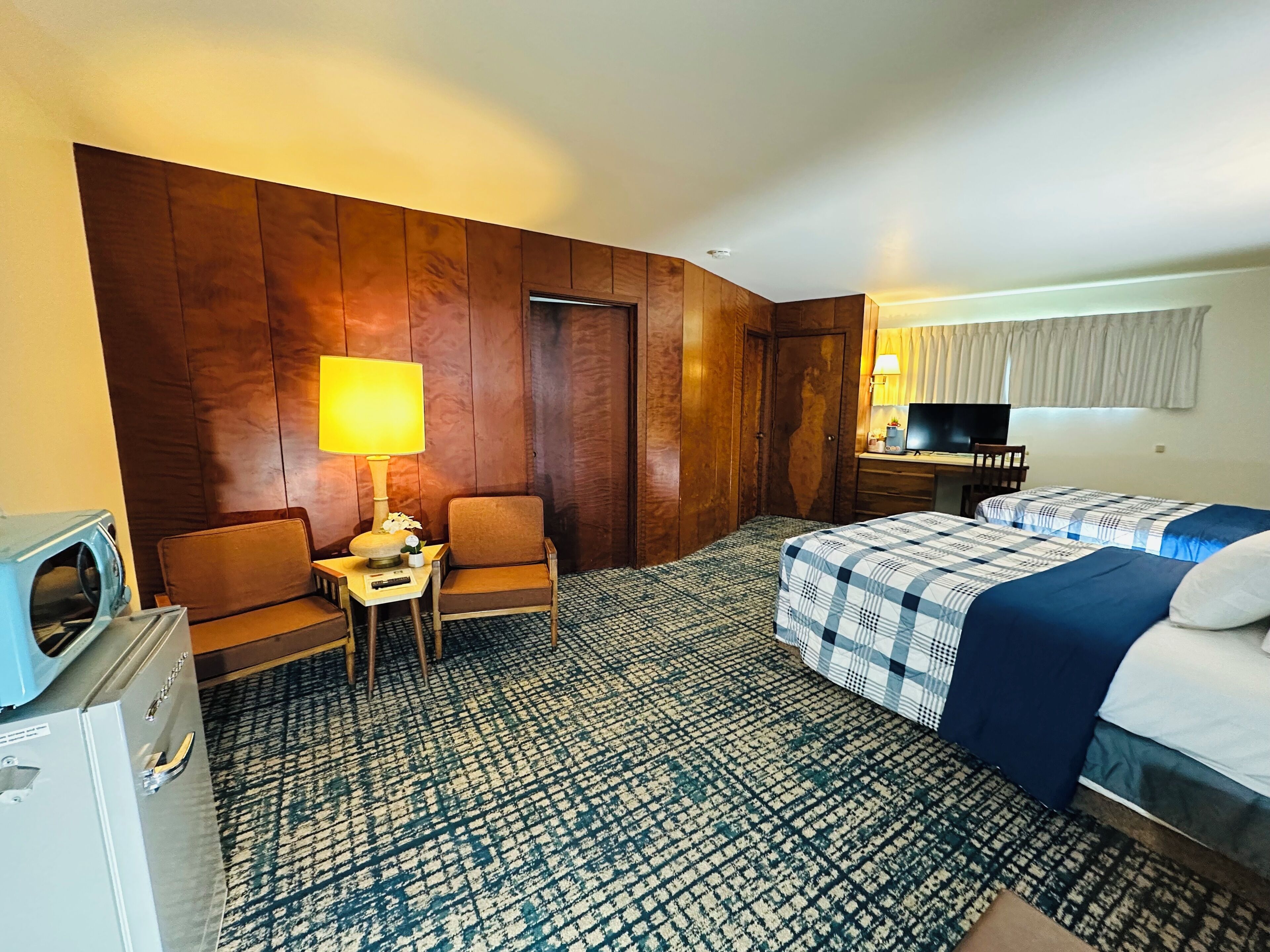 Une chambre d’hôtel équipée d’un lit, d’un bureau, d’une chaise, d’une télévision et d’un mini-bar.
