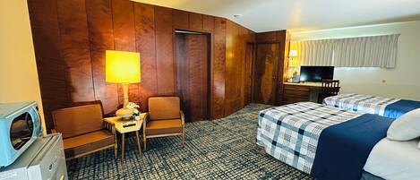 Une chambre d’hôtel équipée d’un lit, d’un bureau, d’une chaise, d’une télévision et d’un mini-bar.