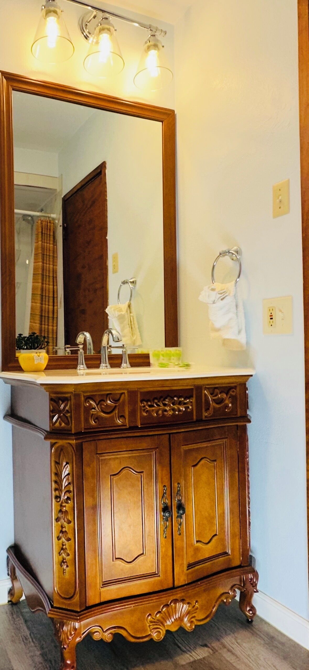 Une coiffeuse en bois avec un grand miroir, un lavabo et un porte-serviettes.
