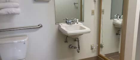A bathroom with a toilet, sink, and mirror.