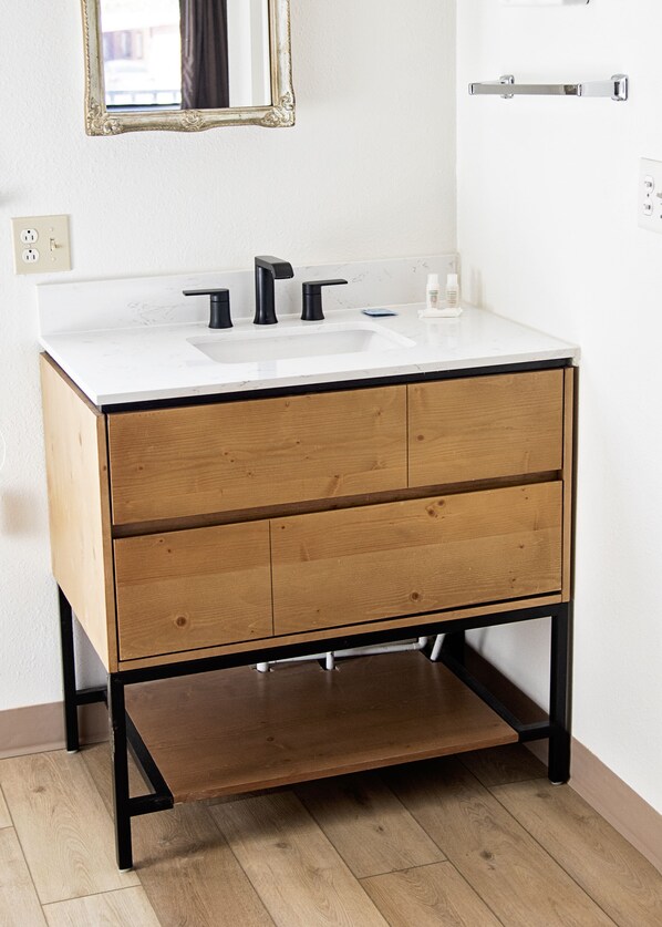 A bathroom with a white sink, black faucets, and wooden cabinets.
