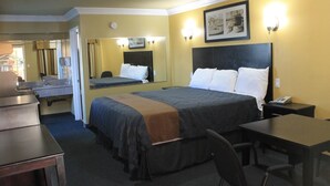 A hotel room with a bed, bedside table, chair, desk, and a bathroom visible through an open door. - El Rancho Inn Hawthorne (Hawthorne)