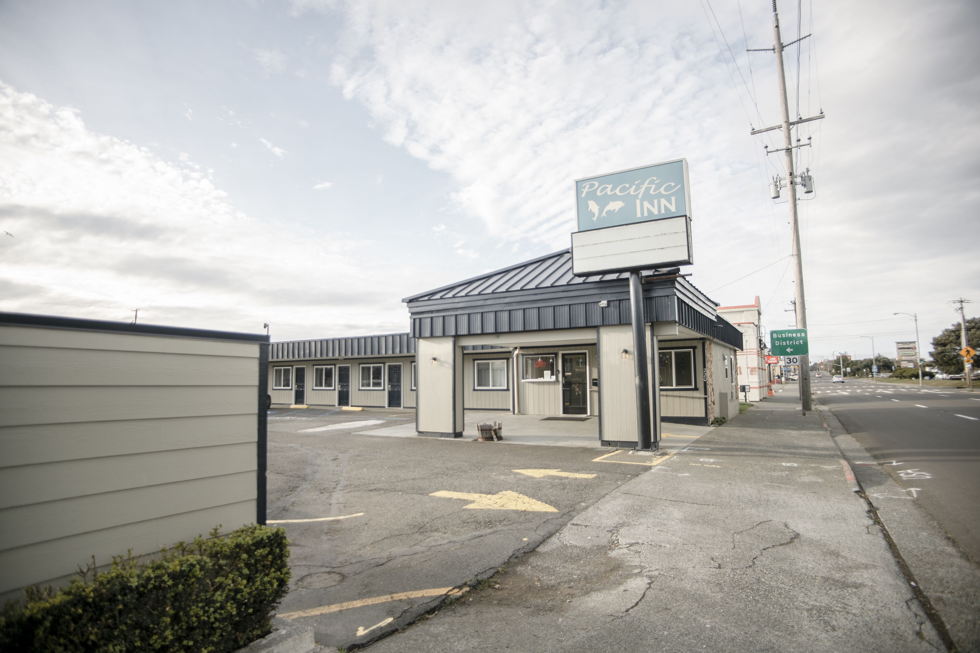 A Pacific Inn motel with a signboard, a parking lot, and a street view.