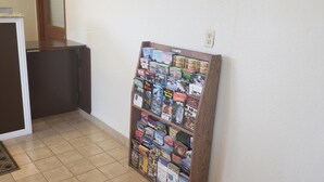 A hallway with a bulletin board filled with magazines and a dark-colored desk with a small stack of papers on top. - Pacific Inn (Crescent City)