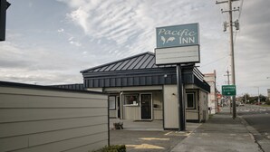 A Pacific Inn building with a signboard, a sidewalk, and a street with a business district sign. - Pacific Inn (Crescent City)