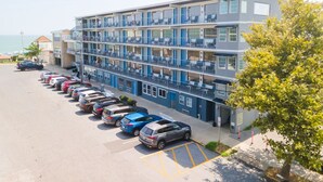 A multi-story hotel with a row of parked cars in front. - Admiral on Baltimore (Rehoboth Beach)