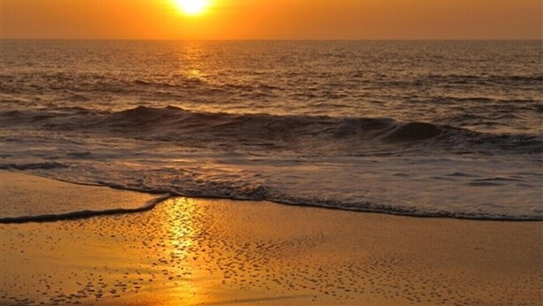 A sunset over the ocean with waves approaching the shore. - Admiral on Baltimore (Rehoboth Beach)