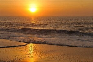 A sunset over the ocean with waves approaching the shore. - Admiral on Baltimore (Rehoboth Beach)