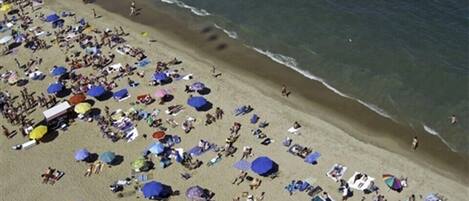 Una playa con muchos sombrillas y gente.