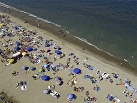 Una spiaggia con numerosi ombrelloni e persone.