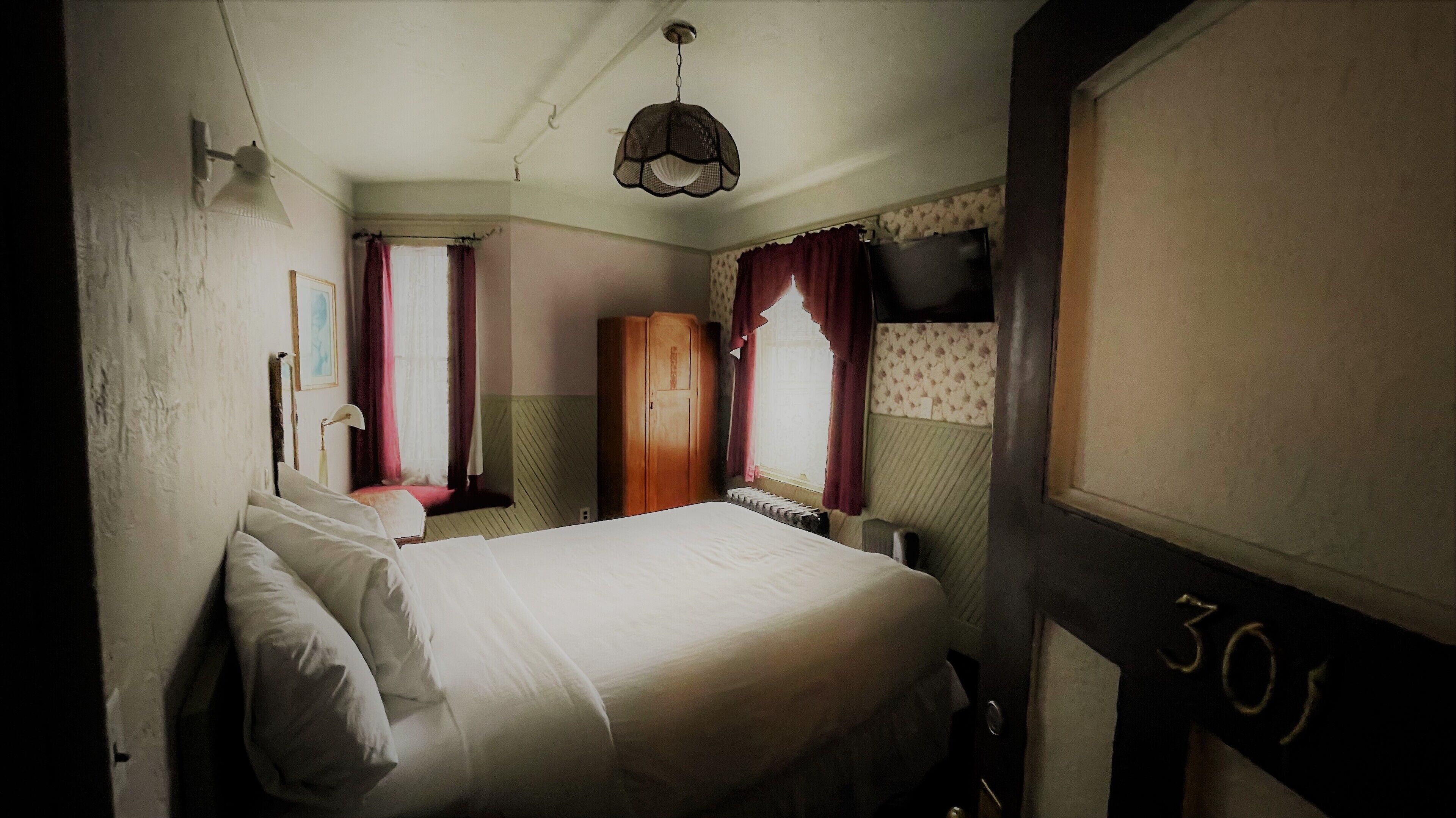 Une chambre à coucher avec un lit, une armoire, un radiateur et une fenêtre avec des rideaux.