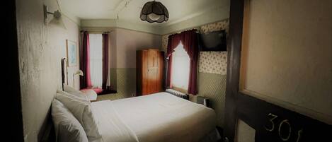 Une chambre à coucher avec un lit, une armoire, un radiateur et une fenêtre avec des rideaux.