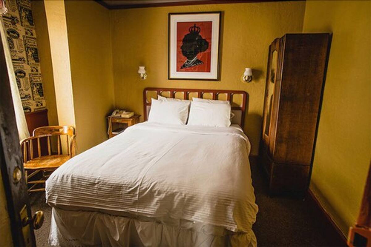 A neatly made bed in a room with a wooden headboard, a nightstand, and a framed picture on the wall.