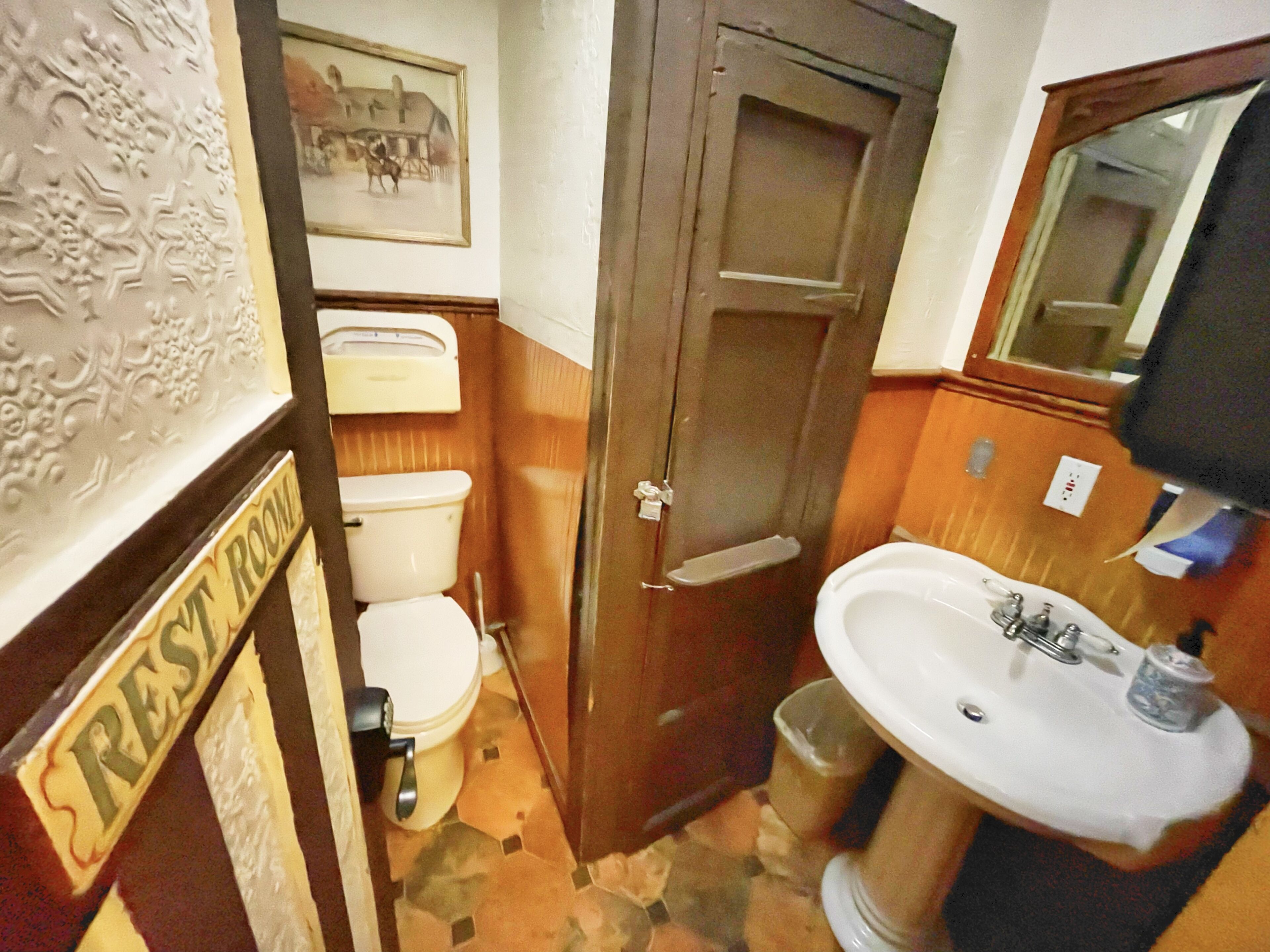 A bathroom with a toilet, sink, and a door leading to another room.