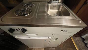 Una cocina compacta con estufa integrada, un lavabo y un refrigerador.