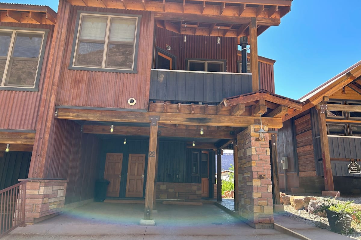 A two-story wooden building with a balcony, a garage, and a stone foundation.