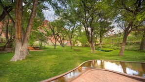 A park with a pond, trees, and a picnic table. - Moab Springs Ranch (Moab)