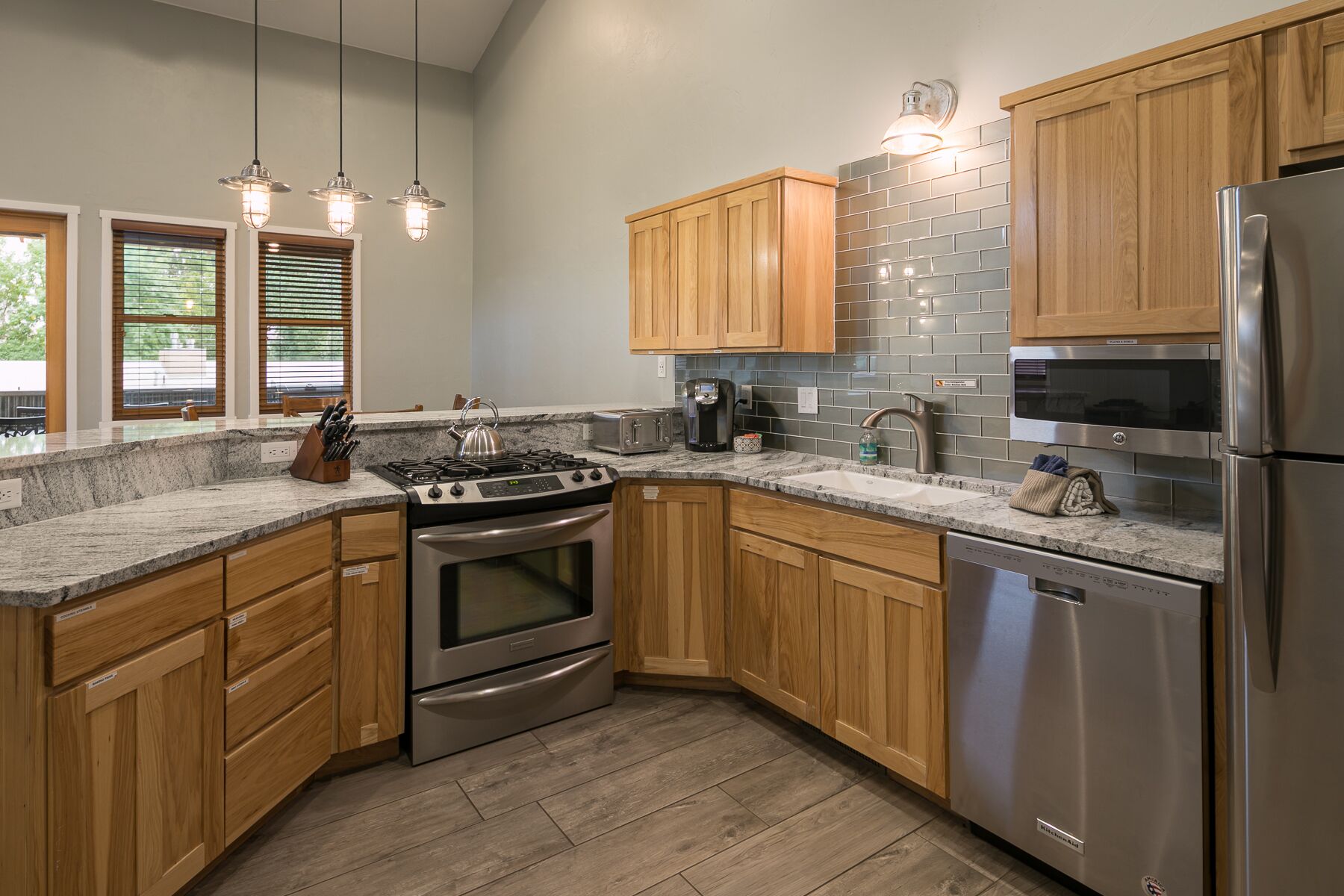 A modern kitchen with wooden cabinets, stainless steel appliances, and a granite countertop.