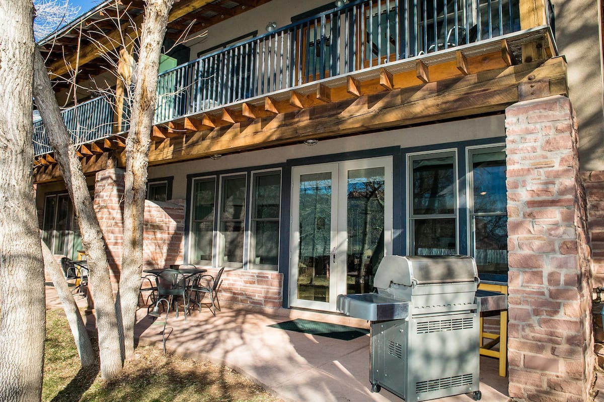A patio area with a grill, outdoor seating, and a view of the building's brick facade and windows.