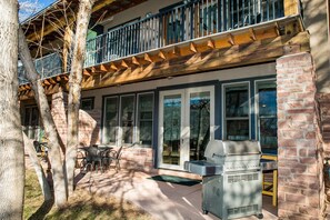 A patio area with a grill, outdoor seating, and a view of the building's brick facade and windows.