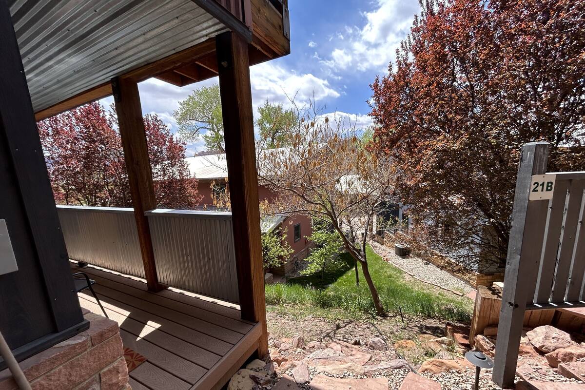 A wooden deck with a metal roof, a stone pathway, and a sign marked '21B'.