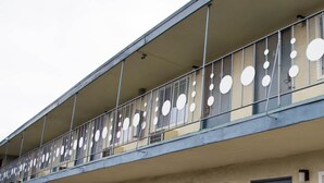 A building with a balcony featuring a metal railing with circular cutouts. - Sahara Motel (Anaheim)