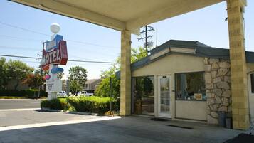 Un motel avec une station-service attenante, reconnaissable à son grand panneau et à son petit bâtiment à la façade en pierre.