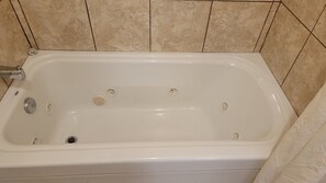 A white bathtub with multiple drain holes, a faucet, and a control knob.