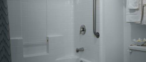 Un baño con una bañera blanca, un inodoro y un pasamanos.