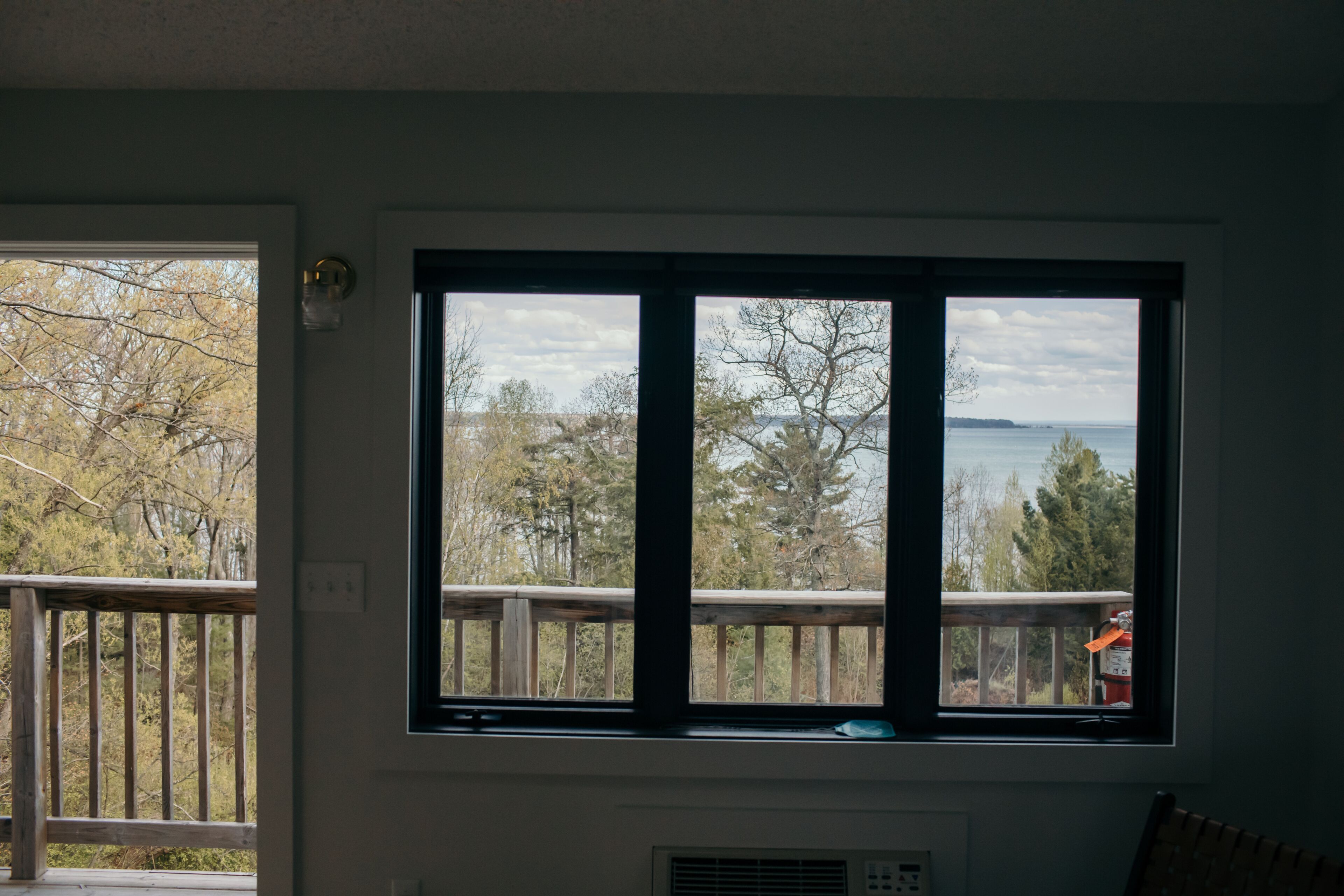 A room with a large window overlooking a deck and a body of water.
