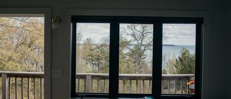 A room with a large window overlooking a deck and a body of water.