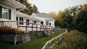 A row of white cabins with wooden railings and a grassy lawn.