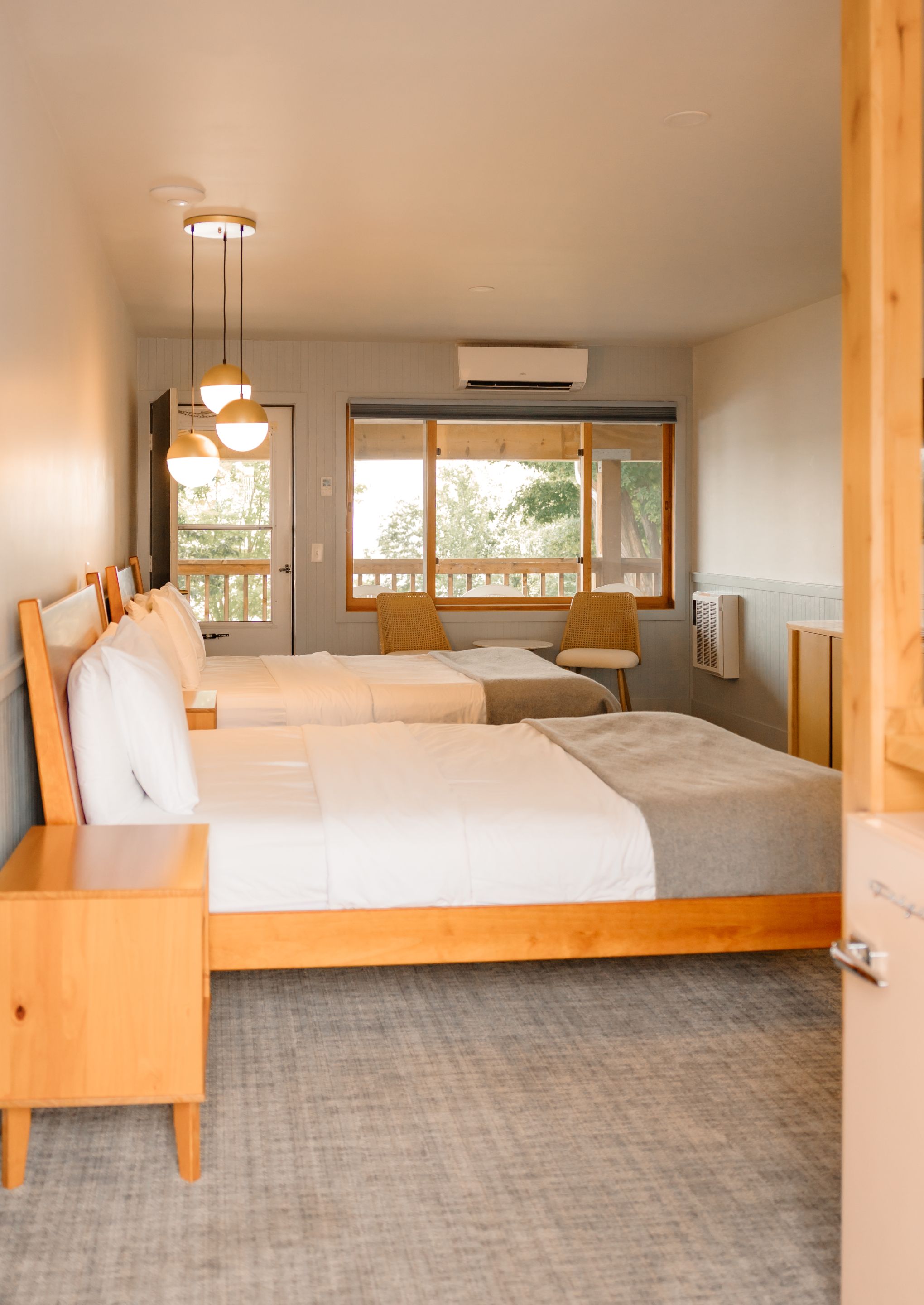 Ein modernes Schlafzimmer mit einem großen Bett, Nachttischen, einer Sitzecke mit einem Sessel und einem Fenster mit Blick.