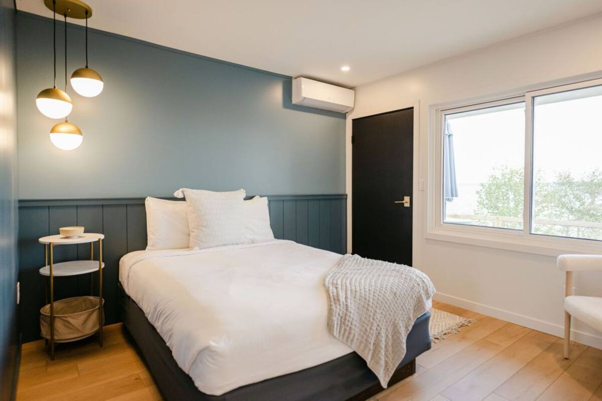 A bedroom with a bed, bedside tables, a window, and a door.