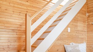 A wooden staircase with white railings leading to a lofted area. A bench with cushions is placed against the wall below the staircase. - Seagull Bay Motel (Bayfield)