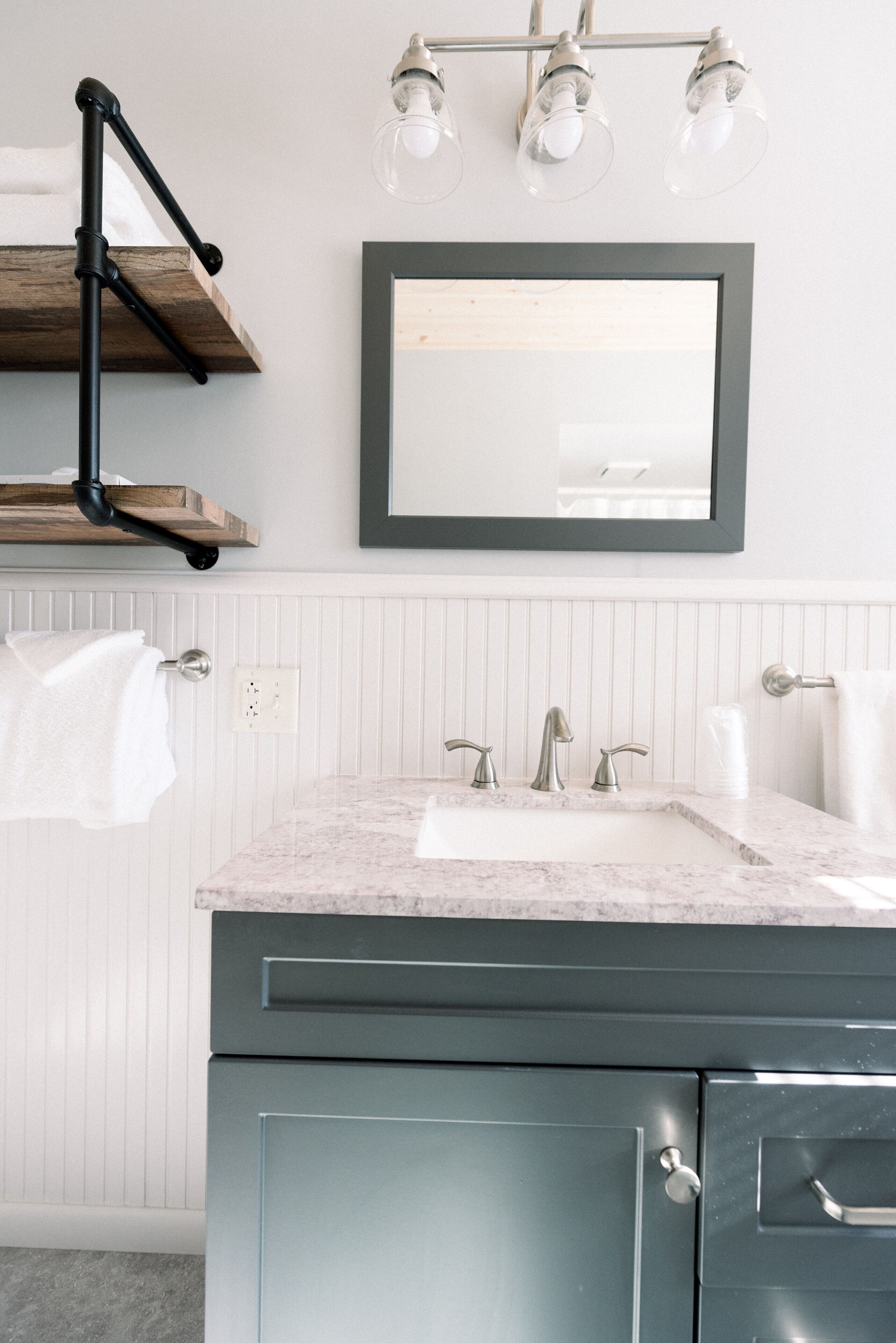 A bathroom with a marble sink, a mirror, and a towel rack.