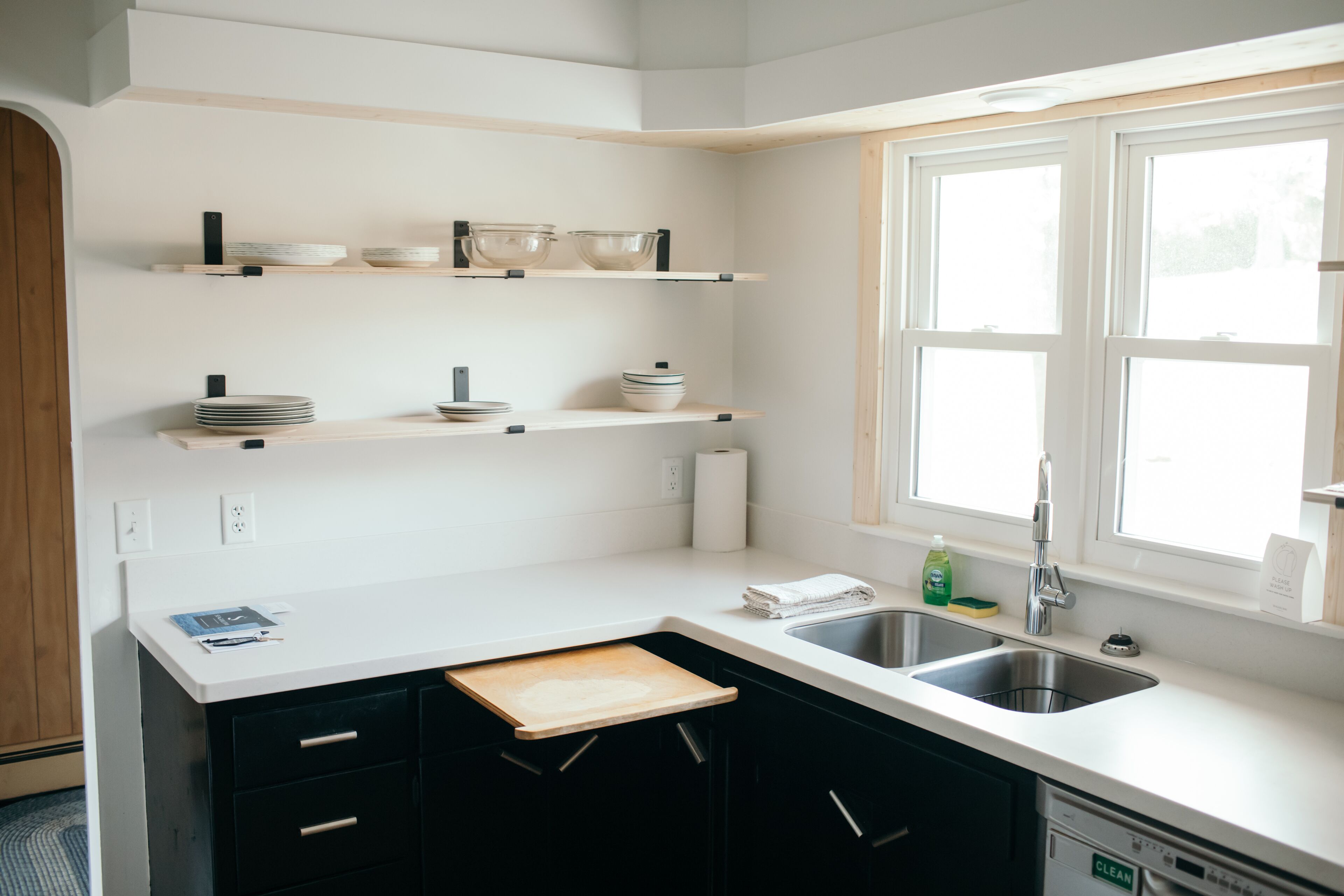 A modern kitchen with white countertops, black cabinets, and built-in shelves.