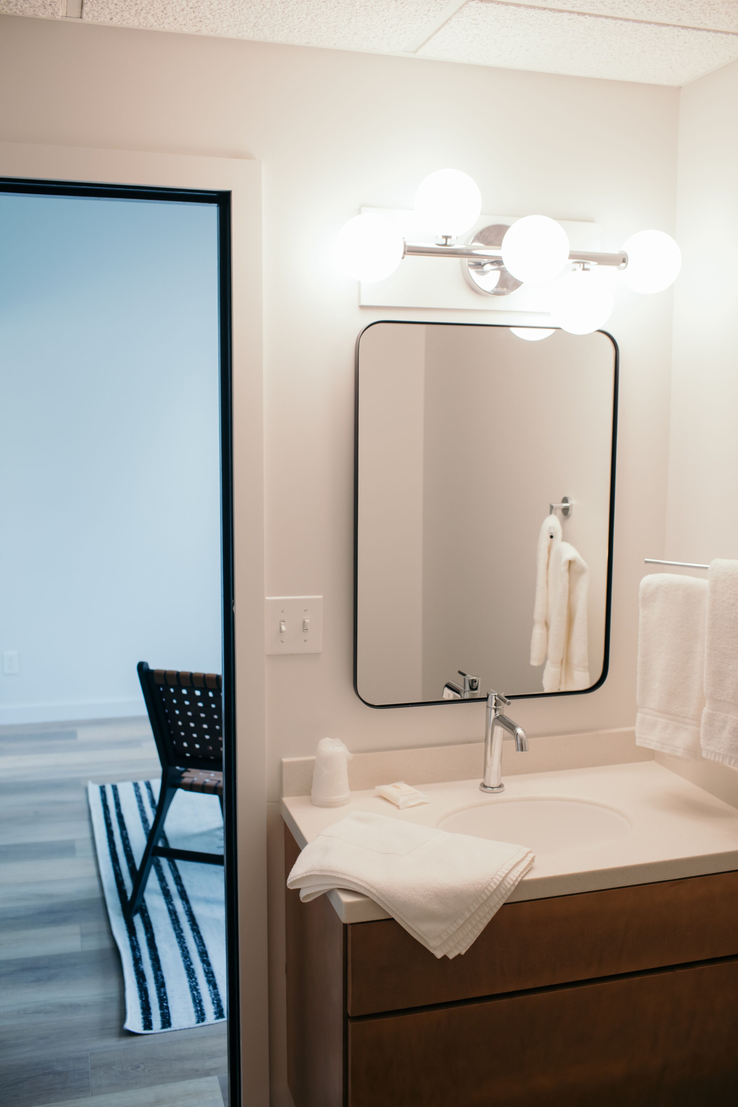 A bathroom with a mirror, vanity, and a towel rack.