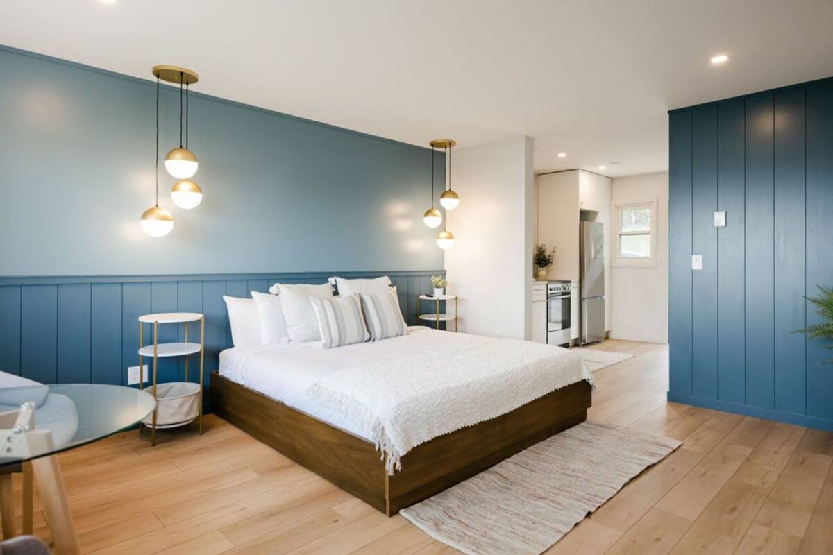 A bedroom with a wooden bed, a glass table, and a blue wall.