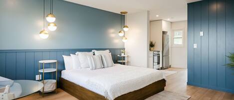 A bedroom with a wooden bed, a glass table, and a blue wall.