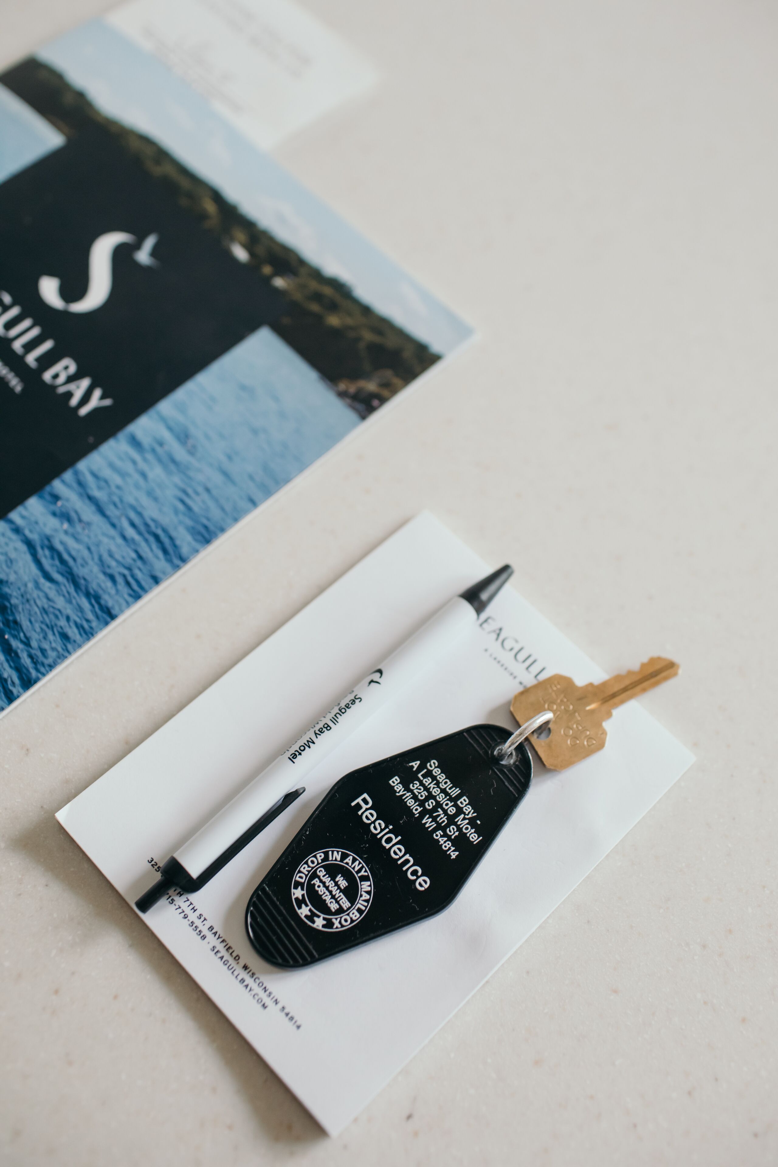 A key, a pen, and a business card on a table.