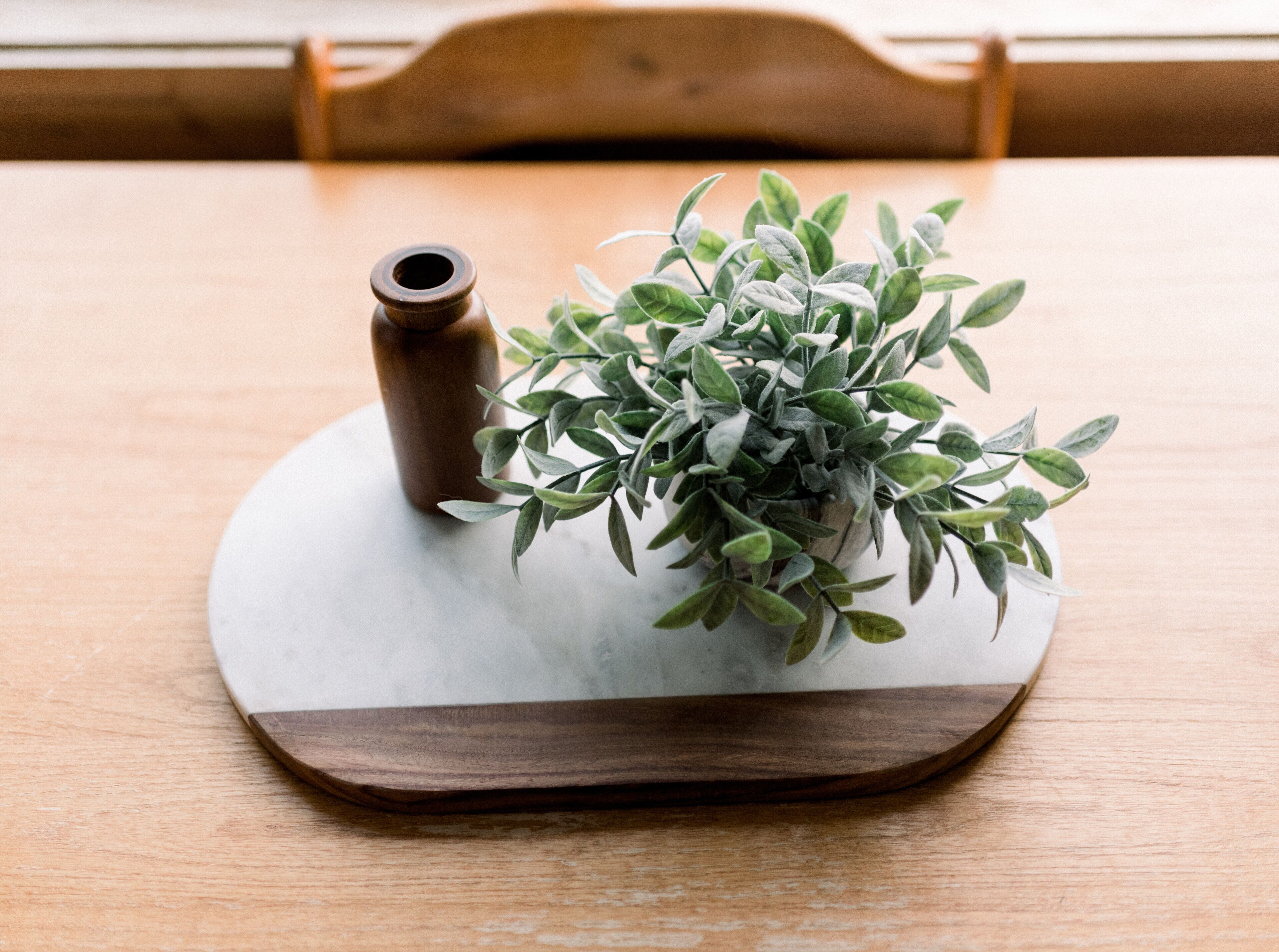 A wooden table with a marble coaster and a small potted plant.